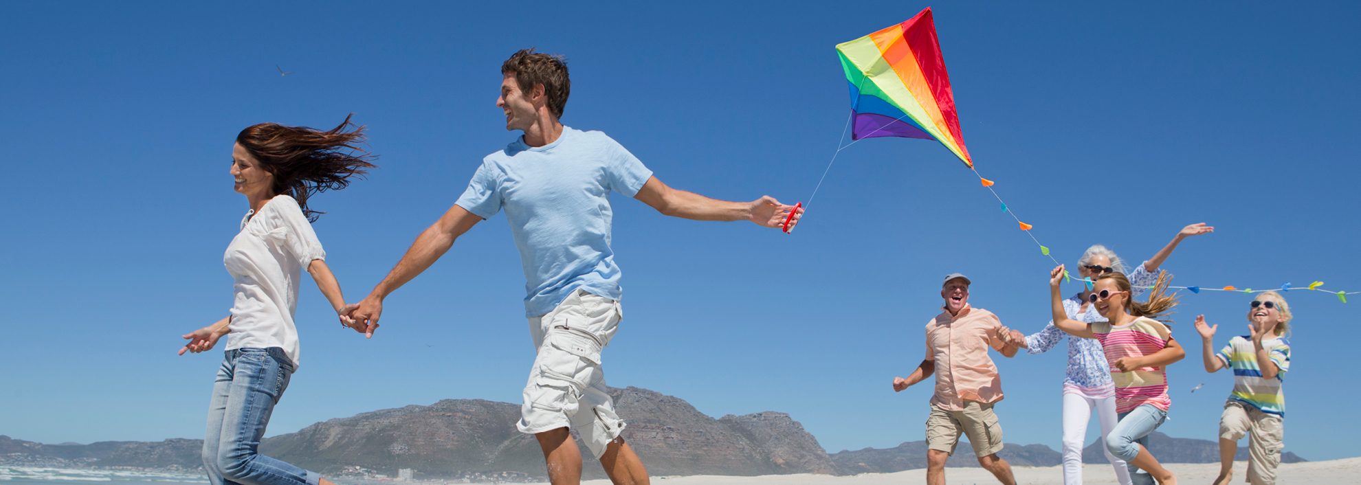 Image of family running down coast with a kite