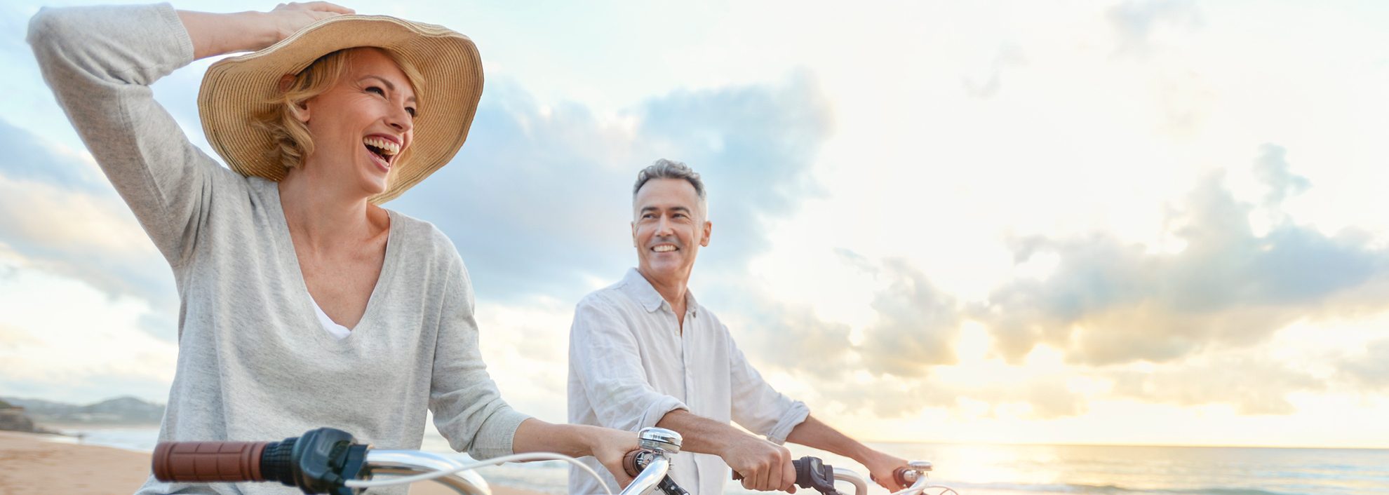 Image of senior couple riding bikes down beach